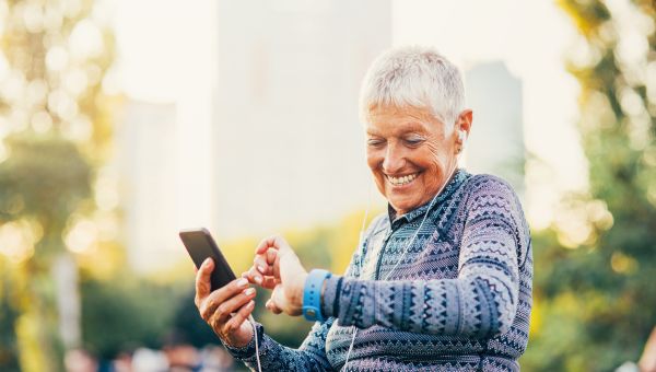 an older white woman with short white hair and a workout short smiles as she looks at her activity tracking smart watch