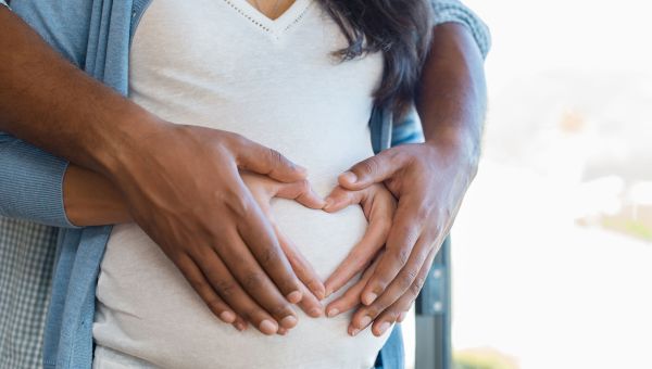 Pregnant woman is cradled by her partner. 