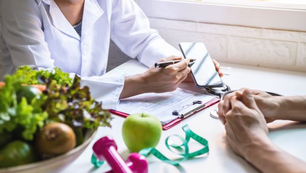 a young male patient sits and speaks with a healthcare provider; we see only the patients and provider's hands as they speak