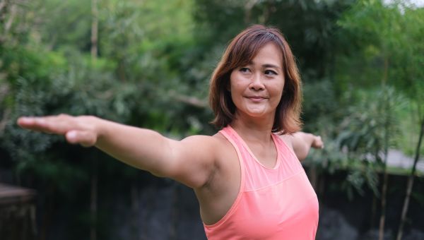 middle-aged woman stretching arms outdoors