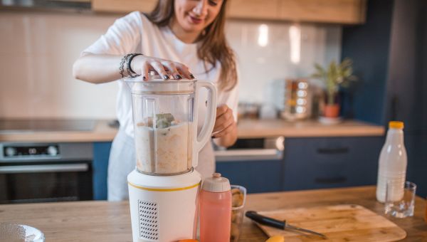 woman preparing banana smoothie in her kitchen