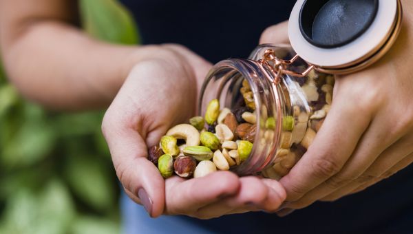 woman pouring a jar of nuts into her hand
