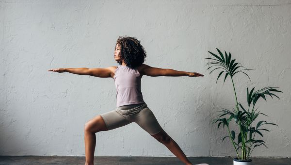 Black woman doing warrior II yoga pose