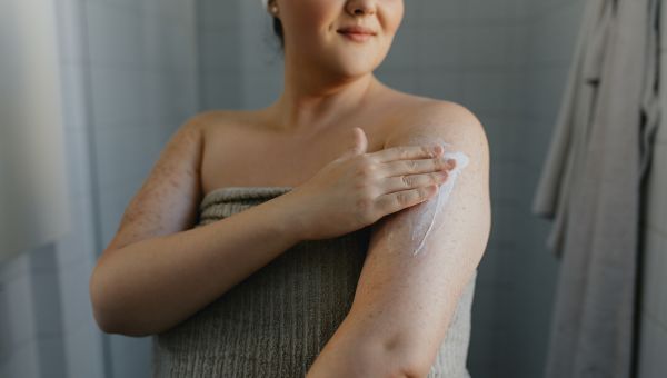 woman in a towel after a shower using scent-free lotion
