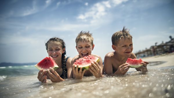 children eating watermelon on the beach