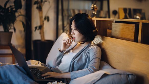 woman watching movie on laptop on her couch 