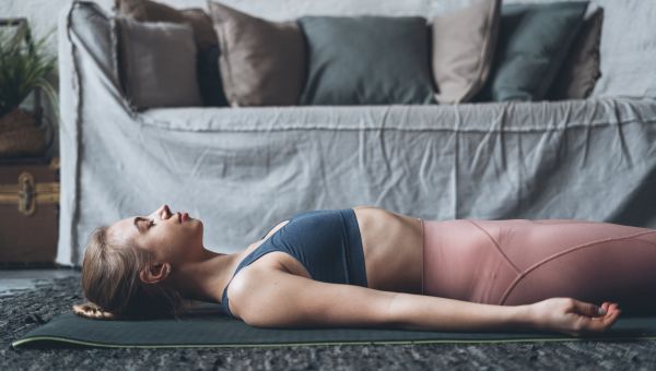young woman lying on a yoga mat with eyes closed