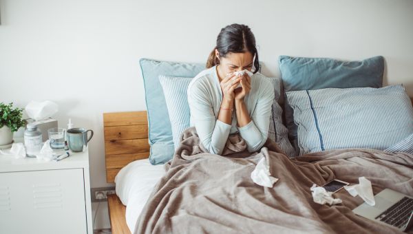 woman in bed sneezing