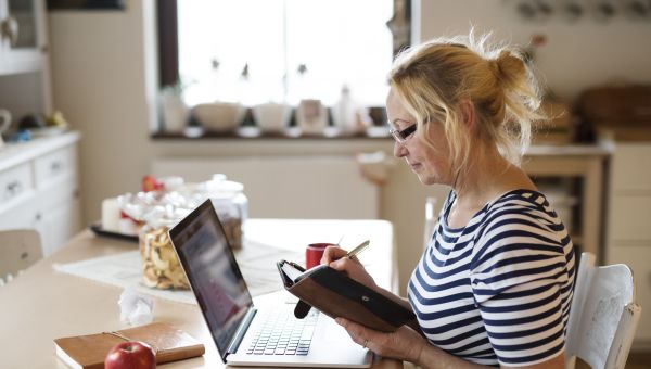 Mature woman online shopping writing in a calendar