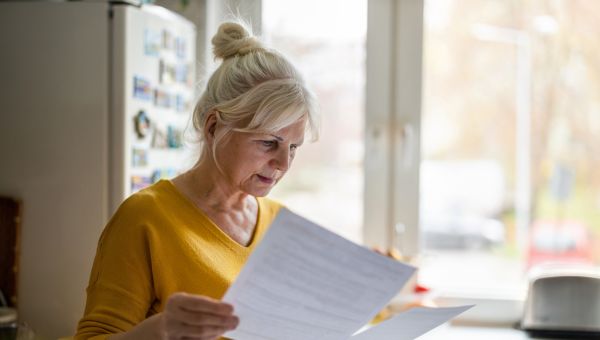 mature woman looking carefully at bills