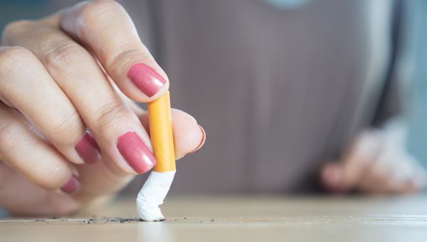 a woman's hands crushing a cigarette