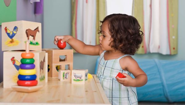 A preschool-aged girl playing with wooden toys and puzzles
