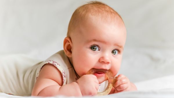 A six-month old baby teething on a rubber ring