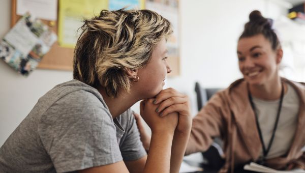 Two friends talking and smiling and controlling their anger through healthy conversation.