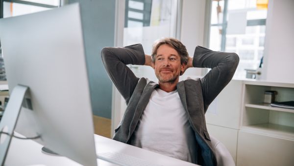 happy white male office worker smiles while looking up from his computer 
