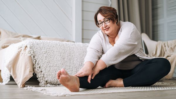 mature woman facing joint replacement surgery stretches in her bedroom