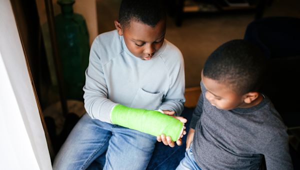 boy showing his brother his broken arm