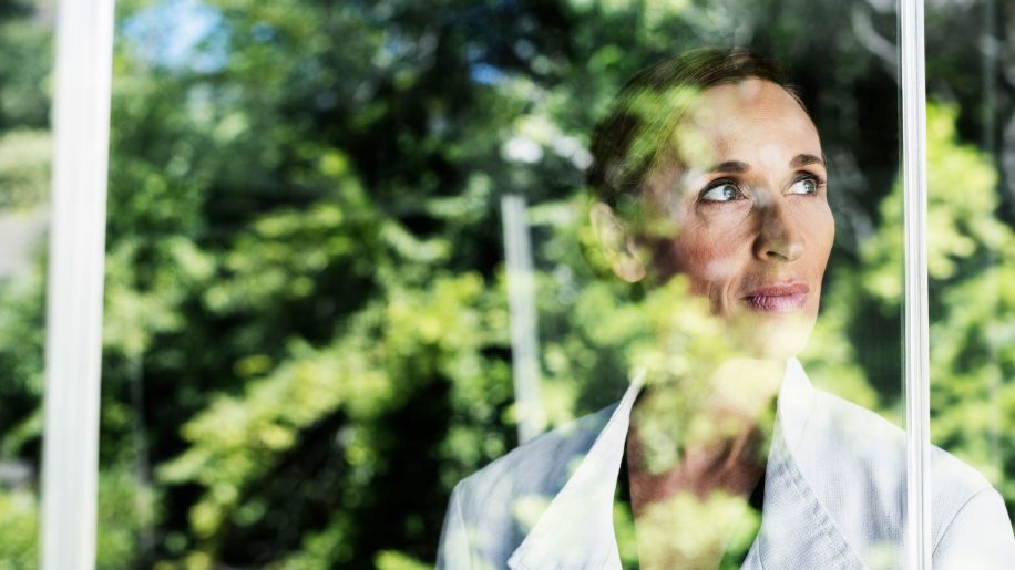 Pensive woman looking through window