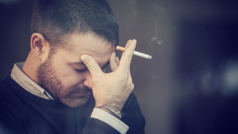 man with a headache smoking