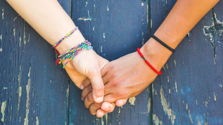 holding hands, bracelets, blue wooden background