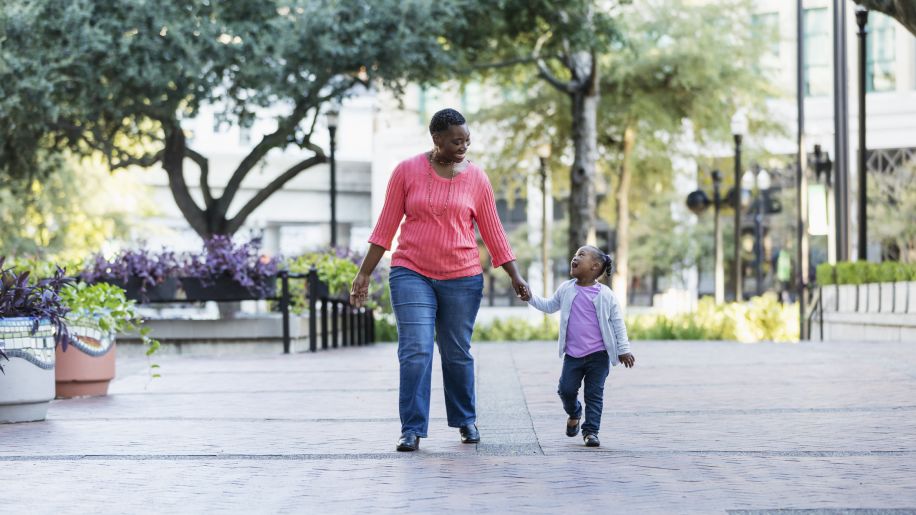 a middle aged Black woman and her young daughter go for a walk in a city