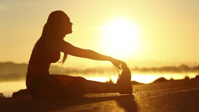 woman doing stretches at sunset