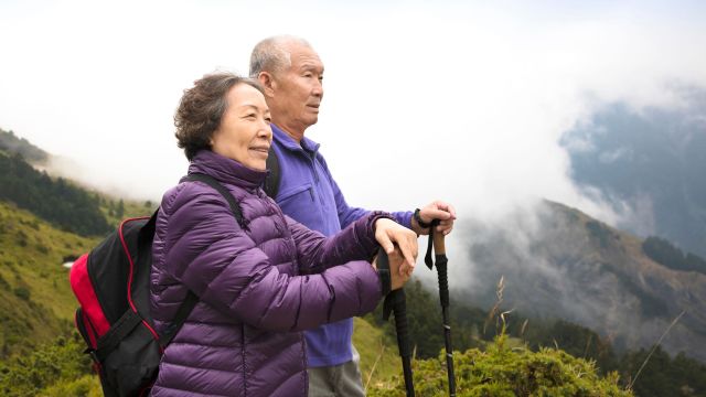 happy asian senior couple hiking on the mountain