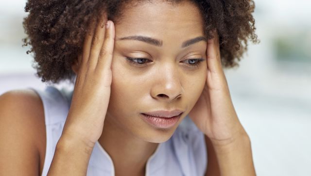 people, emotions, stress and health care concept - unhappy african american young woman touching her head and suffering from headache