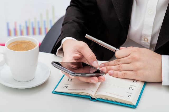 Businesswoman with phone, calendar and a coffee