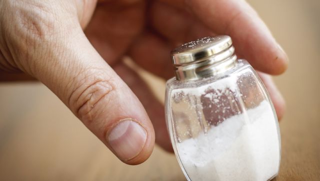 Salt shaker taken by hand from wooden table