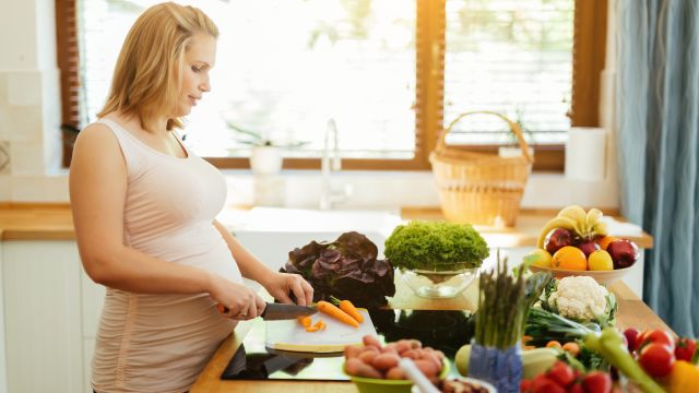pregnant woman chopping food in kitchen