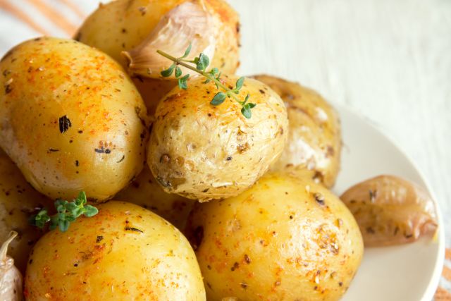Rustic oven baked potatoes with garlic, spices and herbs close up