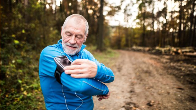 An older man with joint pain adjusts his phone armband as he learns how to start a new exercise-for-beginners program. 