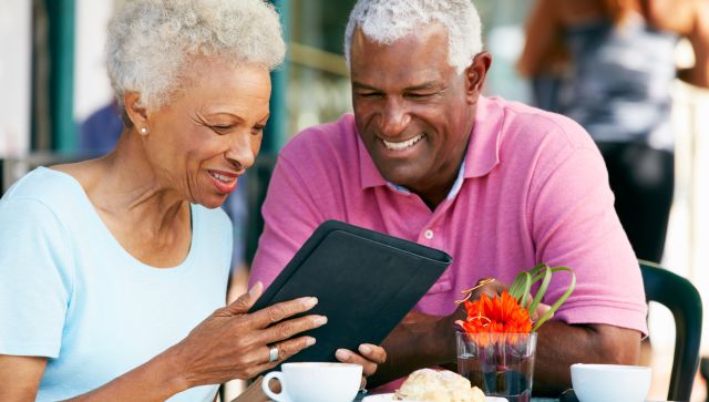 senior couple staring at ipad, tablet at outdoor restaurant