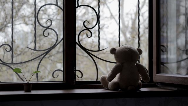 A teddy bear abandoned by a window