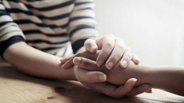 woman consoling her friend by holding her hand