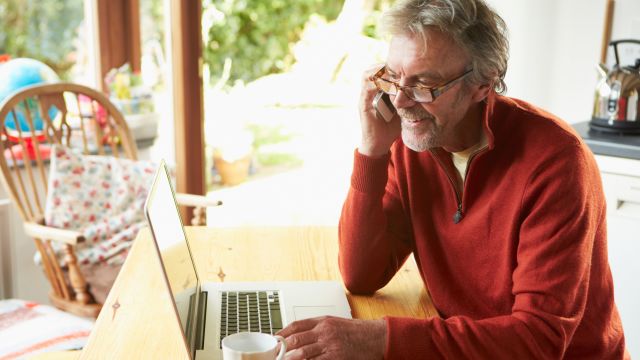 Mature man using mobile phone and laptop