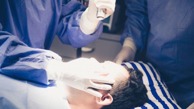 Surgeons examining patient's eyes with flashlight