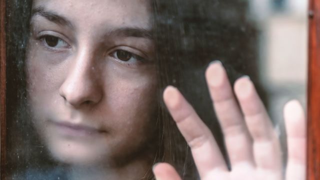 Sad teenage girl looking out window
