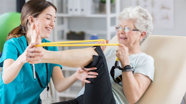 An older woman works with a physical therapist on natural treatments for rheumatoid arthritis swelling and discomfort.