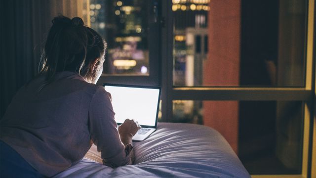 Woman using her laptop while lying in bed