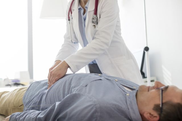 doctor performing abdominal exam on male patient