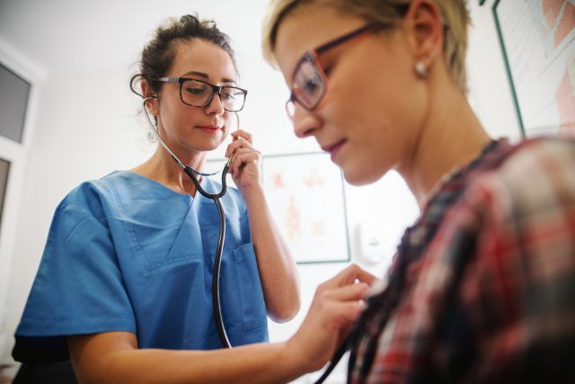 doctor listening to woman's heart