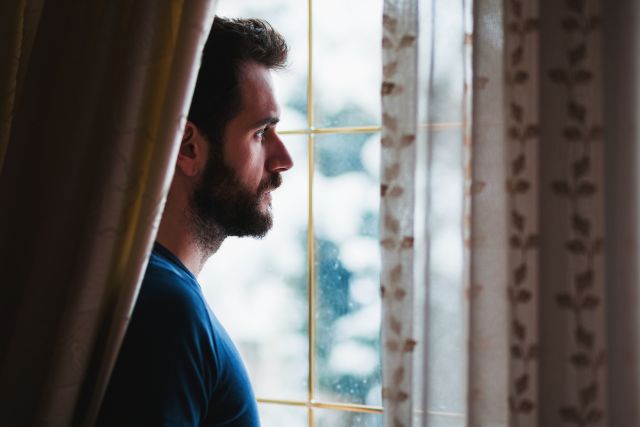 Bearded man looking out window