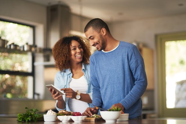 Happy young couple in kitchen eating healthy