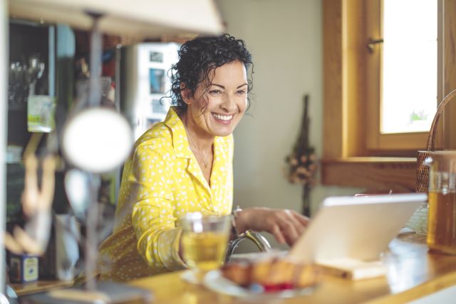 A smiling woman looks online for healthy thyroid diet tips—as well as possible thyroid medicine interactions with food.