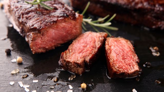 A sliced juicy steak sits on a cutting board—but is eating red meat bad for you?