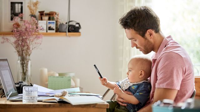 man with baby working on laptop