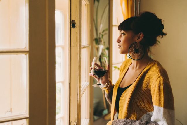 woman with wine glass by window