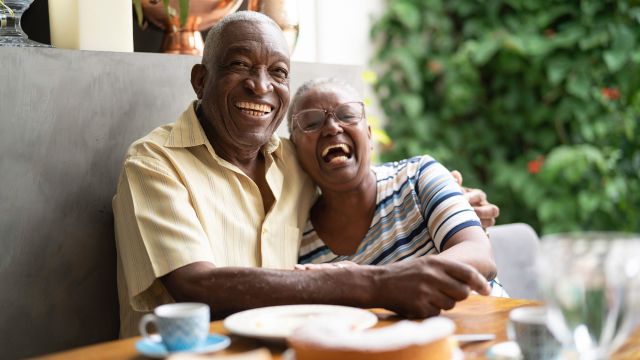 Two seniors laughing over breakfast